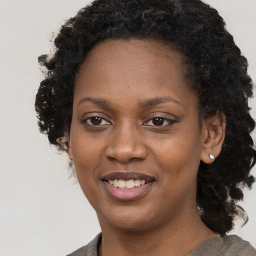 Joyful black young-adult female with long  black hair and brown eyes