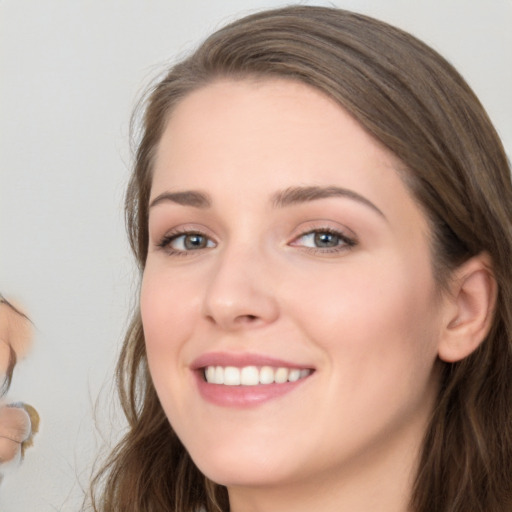 Joyful white young-adult female with long  brown hair and blue eyes