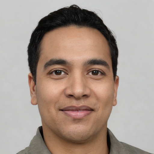 Joyful latino young-adult male with short  black hair and brown eyes