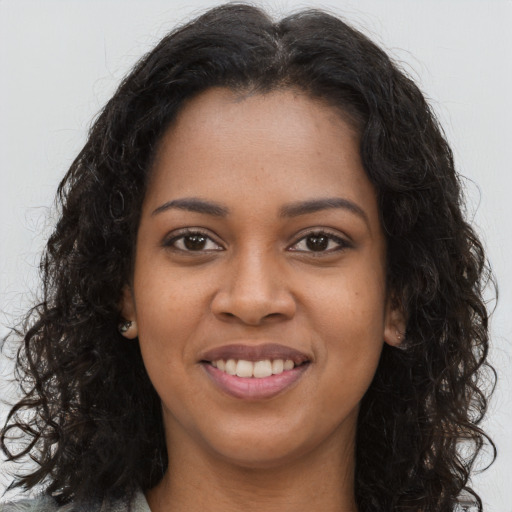 Joyful black young-adult female with long  brown hair and brown eyes