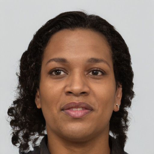 Joyful black young-adult female with long  brown hair and brown eyes