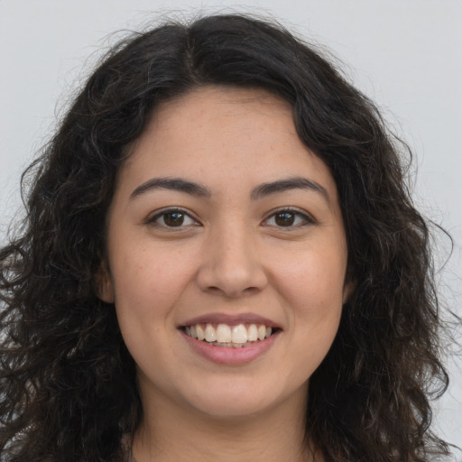 Joyful latino young-adult female with long  brown hair and brown eyes