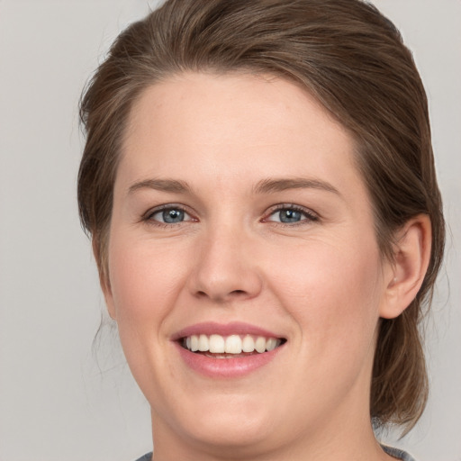 Joyful white young-adult female with medium  brown hair and grey eyes