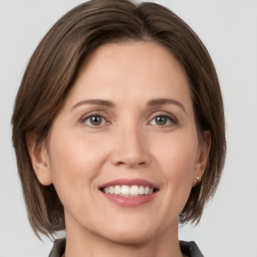 Joyful white young-adult female with medium  brown hair and grey eyes