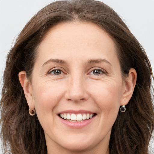 Joyful white adult female with long  brown hair and grey eyes