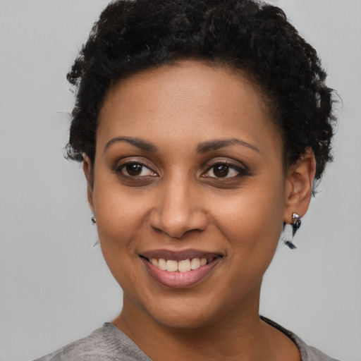 Joyful black young-adult female with short  black hair and brown eyes