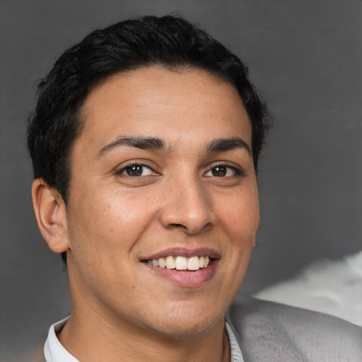 Joyful latino young-adult male with short  brown hair and brown eyes