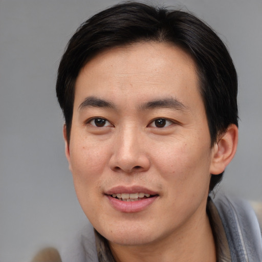 Joyful asian adult male with short  brown hair and brown eyes
