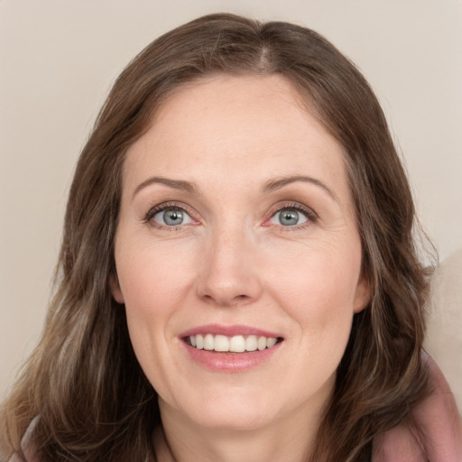 Joyful white adult female with long  brown hair and grey eyes