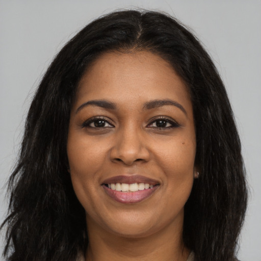 Joyful black young-adult female with long  brown hair and brown eyes