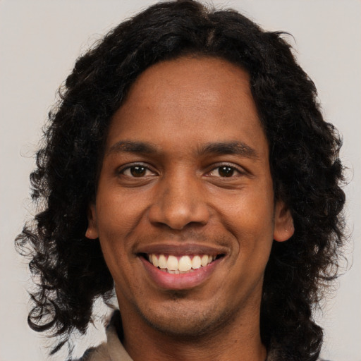 Joyful black young-adult male with long  black hair and brown eyes