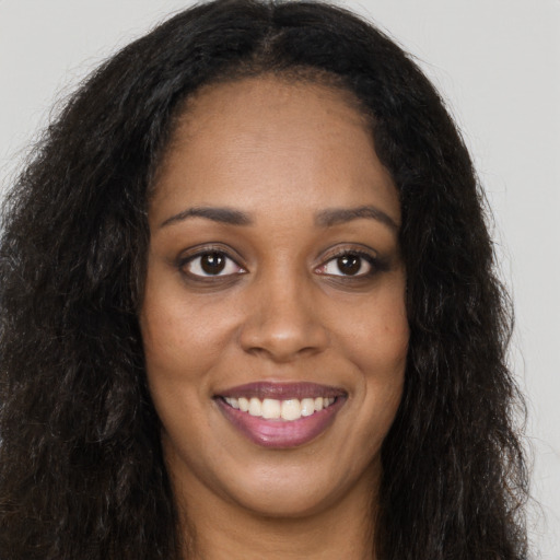 Joyful black young-adult female with long  brown hair and brown eyes