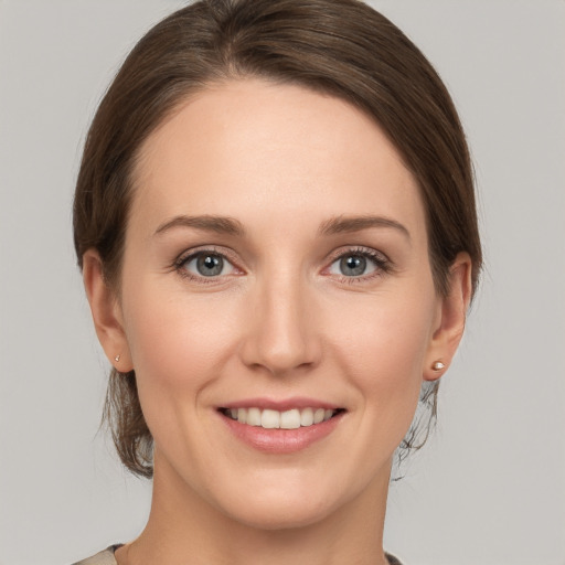 Joyful white young-adult female with medium  brown hair and grey eyes