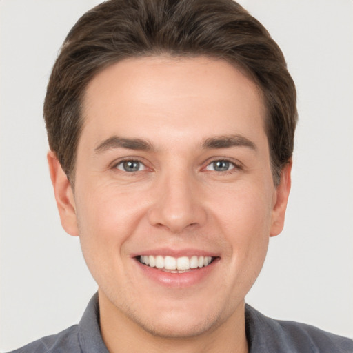 Joyful white young-adult male with short  brown hair and grey eyes