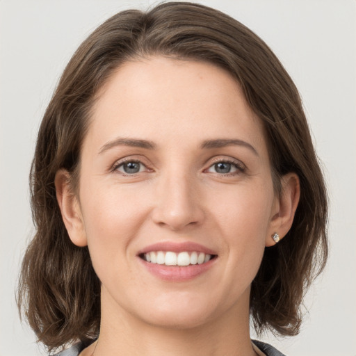 Joyful white young-adult female with medium  brown hair and grey eyes