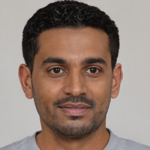 Joyful black young-adult male with short  black hair and brown eyes