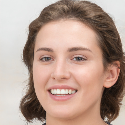 Joyful white young-adult female with medium  brown hair and green eyes