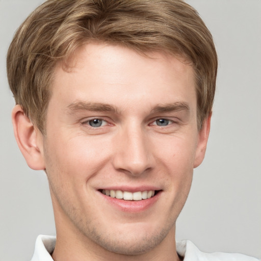 Joyful white young-adult male with short  brown hair and grey eyes