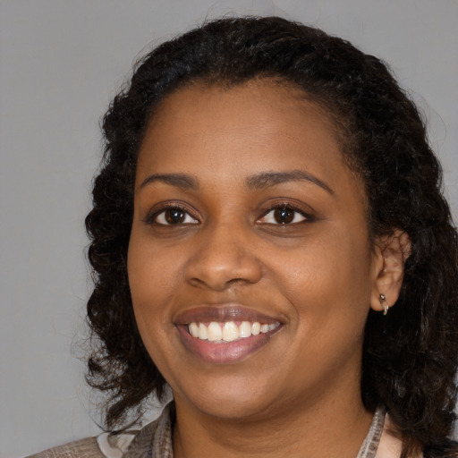 Joyful black young-adult female with long  brown hair and brown eyes