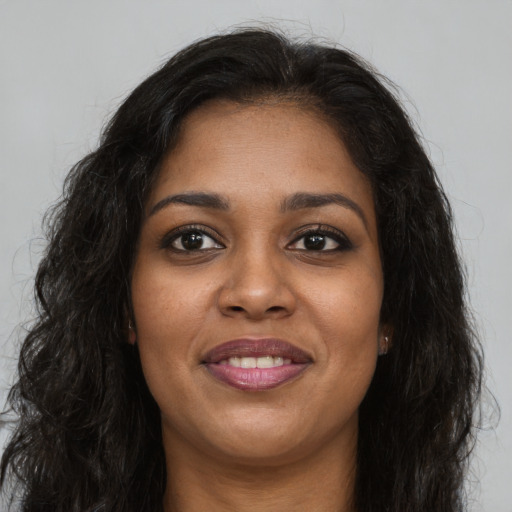 Joyful black young-adult female with long  brown hair and brown eyes
