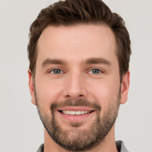 Joyful white young-adult male with short  brown hair and grey eyes