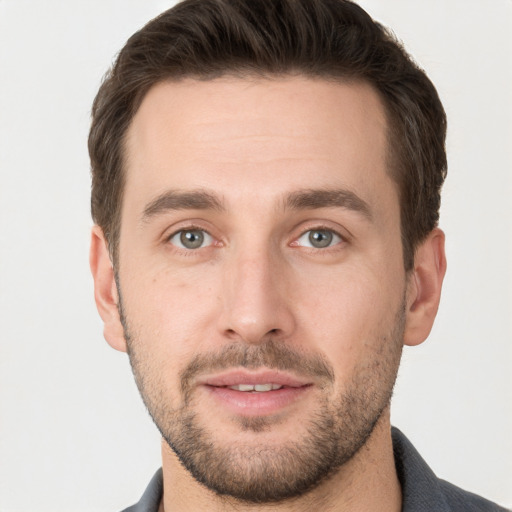 Joyful white young-adult male with short  brown hair and grey eyes