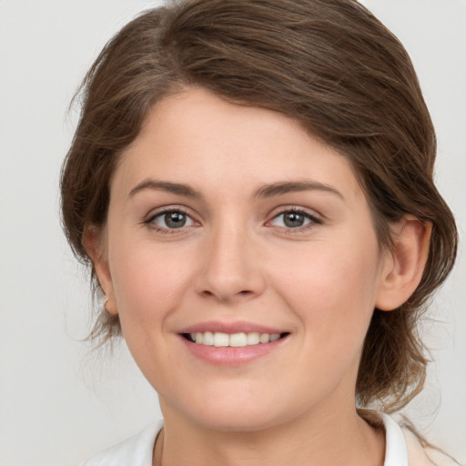 Joyful white young-adult female with medium  brown hair and grey eyes