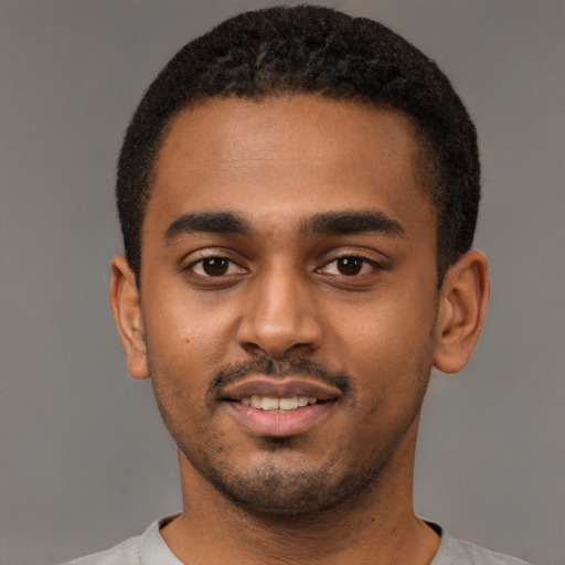 Joyful black young-adult male with short  black hair and brown eyes