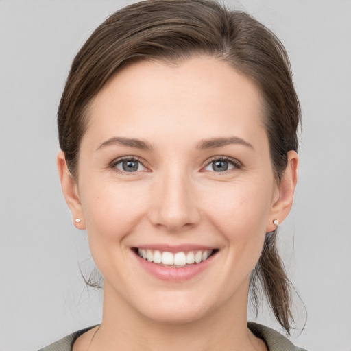 Joyful white young-adult female with medium  brown hair and grey eyes