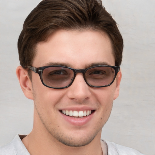 Joyful white young-adult male with short  brown hair and blue eyes