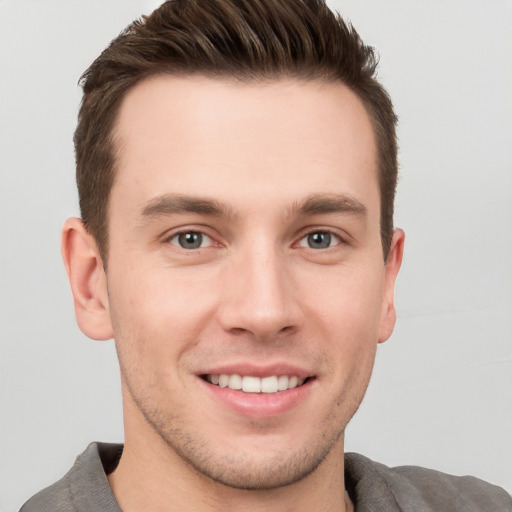 Joyful white young-adult male with short  brown hair and grey eyes