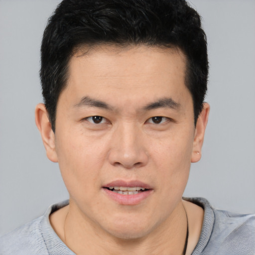 Joyful asian young-adult male with short  brown hair and brown eyes