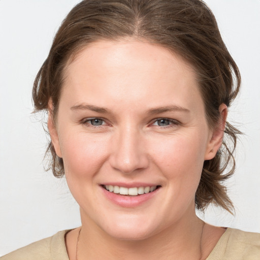 Joyful white young-adult female with medium  brown hair and grey eyes