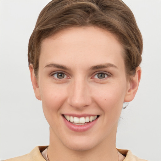 Joyful white young-adult female with short  brown hair and grey eyes