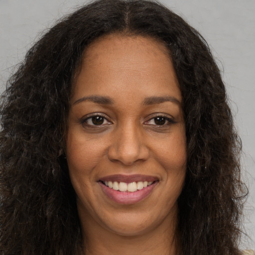 Joyful black young-adult female with long  brown hair and brown eyes