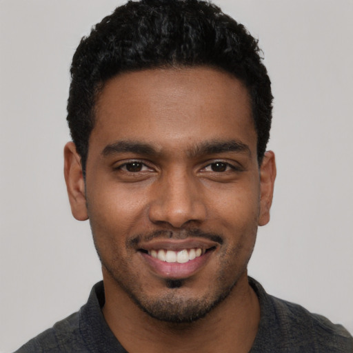 Joyful black young-adult male with short  black hair and brown eyes