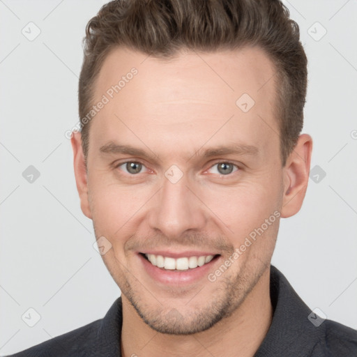 Joyful white young-adult male with short  brown hair and grey eyes