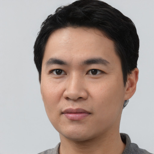 Joyful asian young-adult male with short  black hair and brown eyes