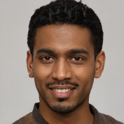 Joyful black young-adult male with short  black hair and brown eyes