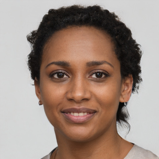 Joyful black young-adult female with short  black hair and brown eyes