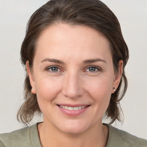 Joyful white young-adult female with medium  brown hair and grey eyes