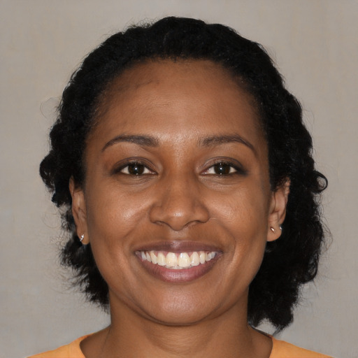Joyful black adult female with medium  brown hair and brown eyes