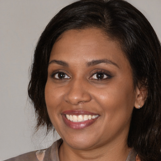 Joyful black young-adult female with medium  brown hair and brown eyes