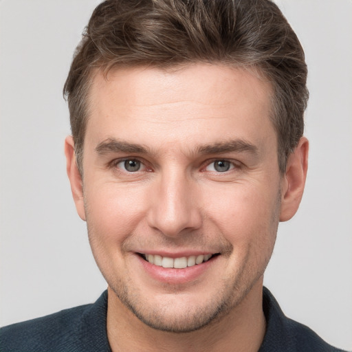 Joyful white young-adult male with short  brown hair and grey eyes