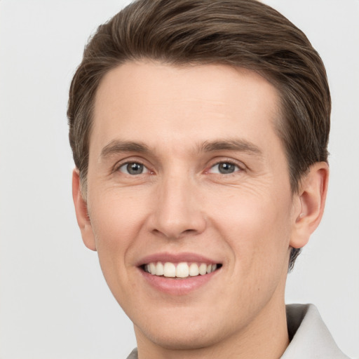 Joyful white young-adult male with short  brown hair and grey eyes