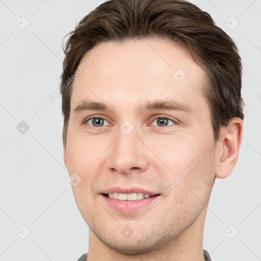 Joyful white young-adult male with short  brown hair and grey eyes