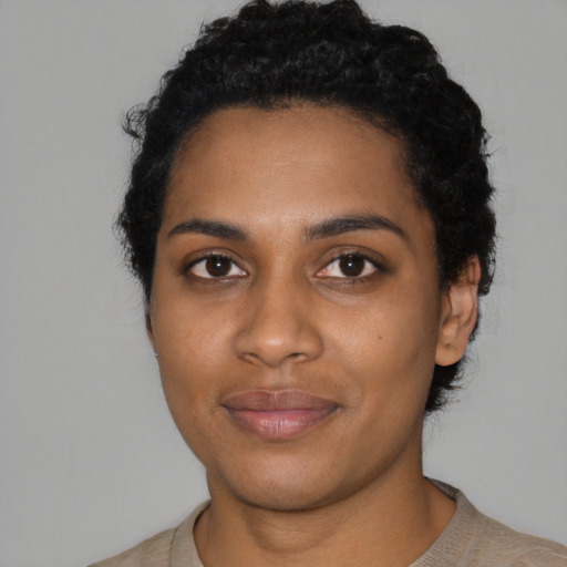 Joyful black young-adult female with short  black hair and brown eyes