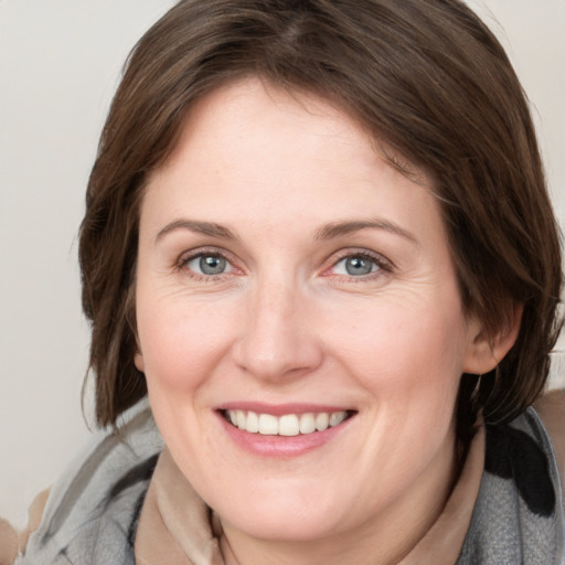 Joyful white adult female with medium  brown hair and grey eyes