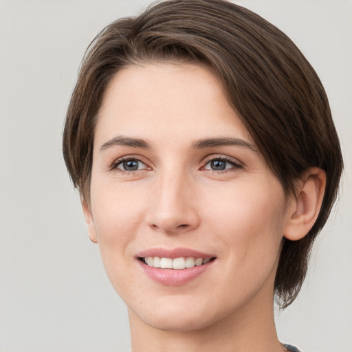 Joyful white young-adult female with medium  brown hair and grey eyes