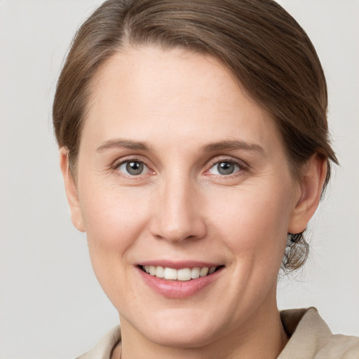 Joyful white young-adult female with medium  brown hair and grey eyes